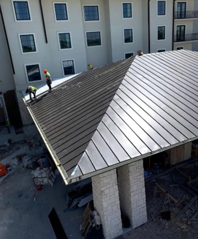 Crew installing standing seam metal roof panels on a commercial project in Kennewick